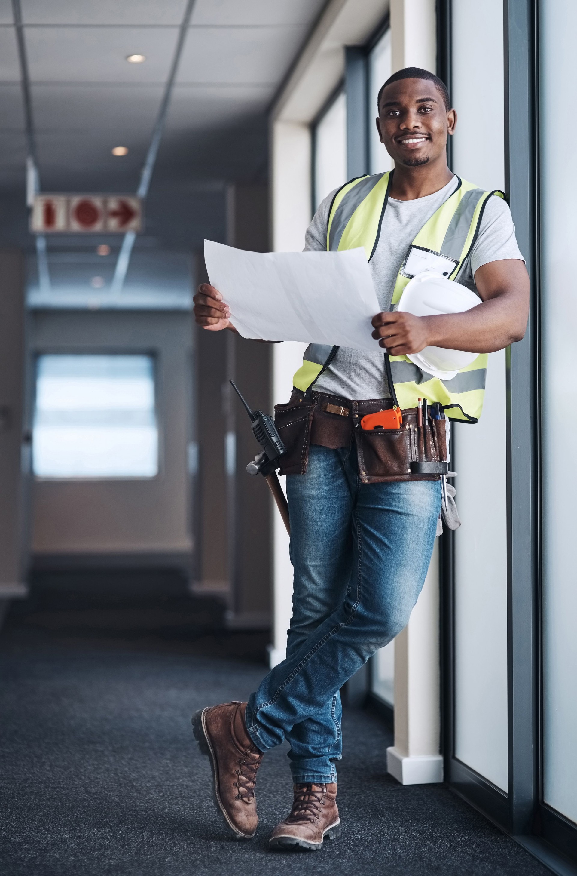 Shot of a handsome young contractor standing alone in a building and holding the floor plan