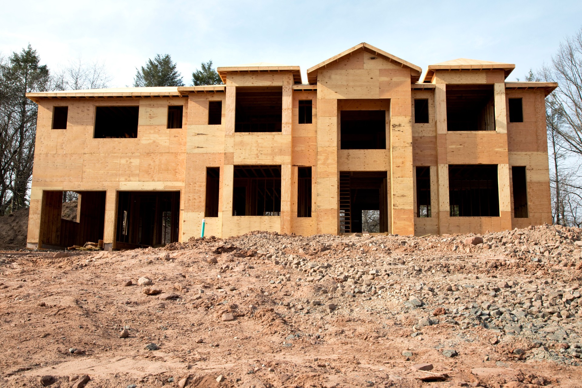 Large home in sheathing stage of construction dirt in foreground